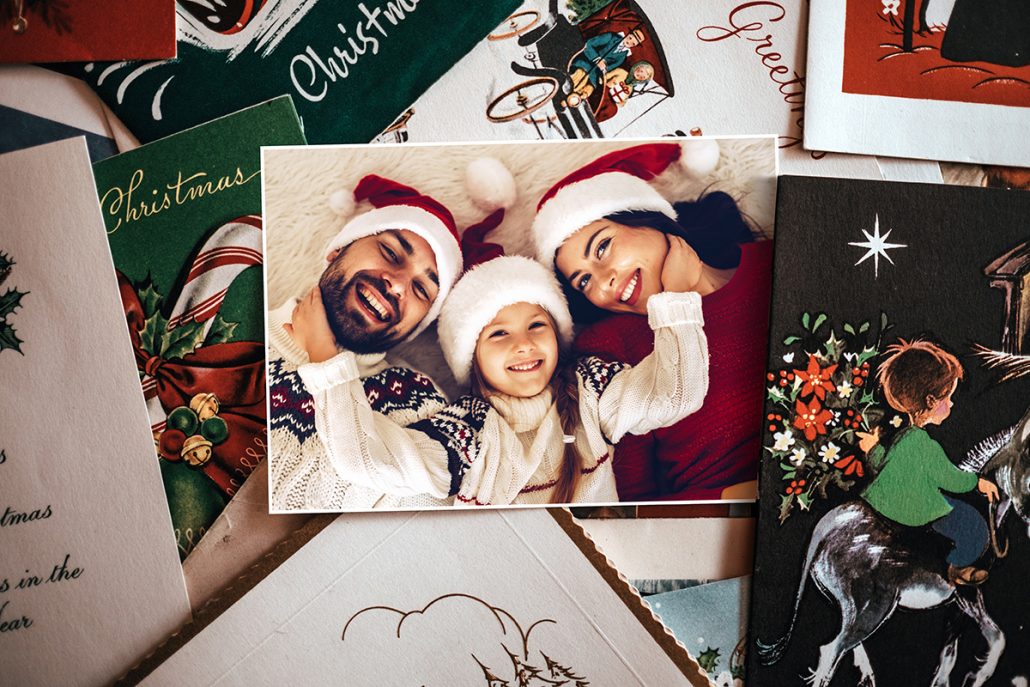 Verschiedene Postkarten zu Weihnachten. Unter anderem lachende Familie mit Weihnachtsmützen auf Postkarte.